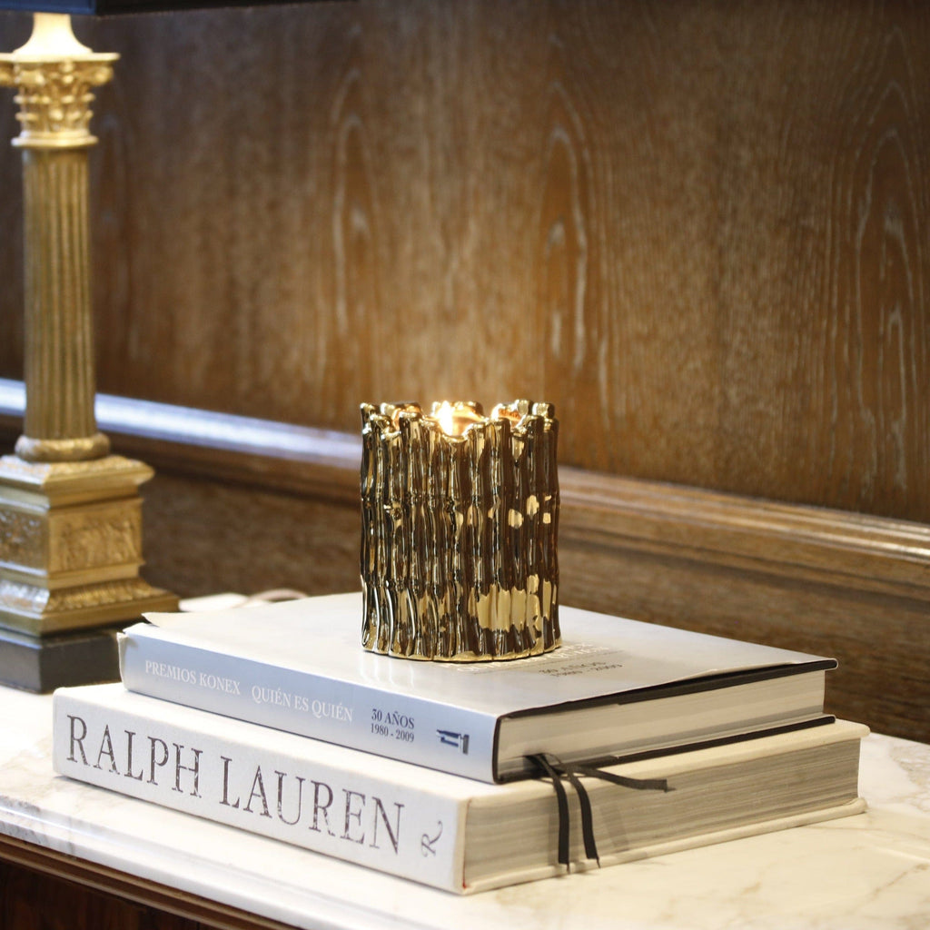 gold sagano candle on a stack of hardcover books