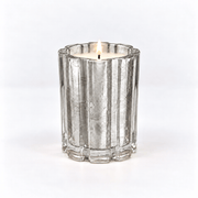 A silver-toned fluted glass candle holder containing a lit white candle, centered on a clean white background.