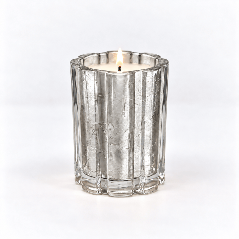 A silver-toned fluted glass candle holder containing a lit white candle, centered on a clean white background.